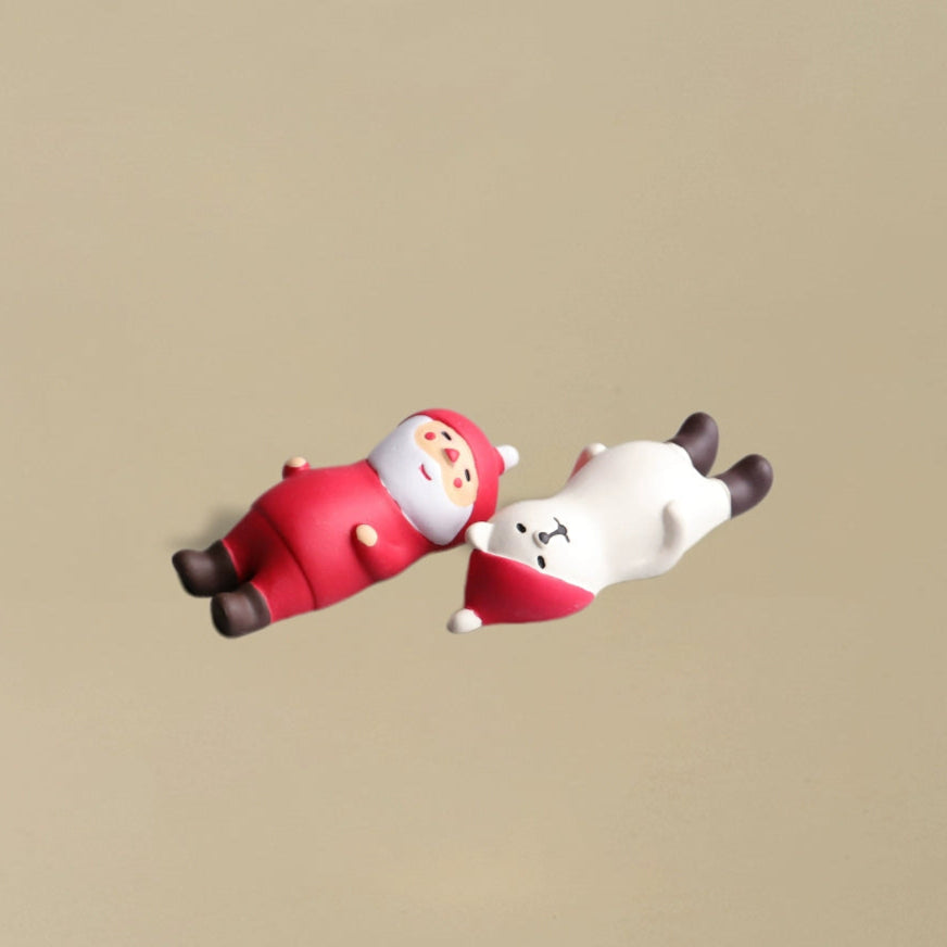 Santa Claus and a polar bear lying flat on the ground together in a playful pose, charming Christmas decoration.