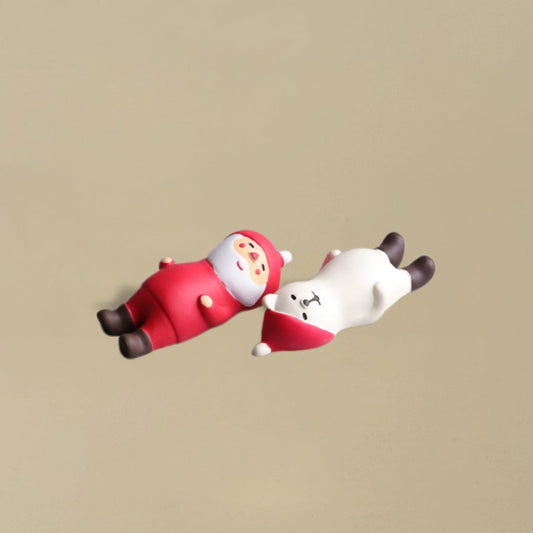 Santa Claus and a polar bear lying flat on the ground together in a playful pose, charming Christmas decoration.